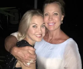 Two women smiling and embracing each other in a close-up portrait at night.