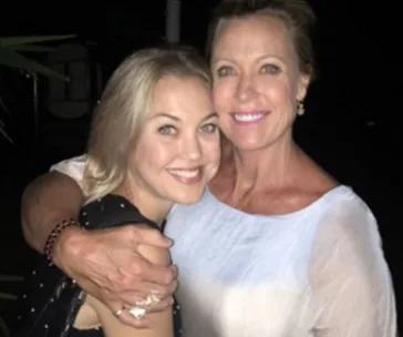 Two women smiling and embracing each other in a close-up portrait at night.