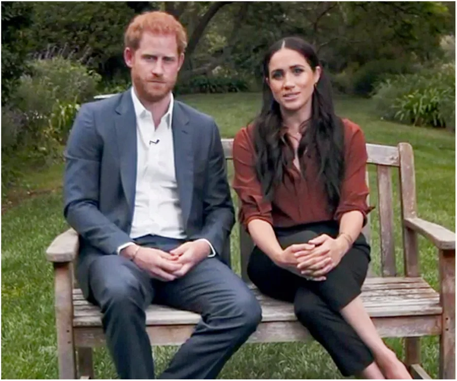 Prince Harry and Meghan Markle seated on a garden bench, appearing in a casual outdoor setting.