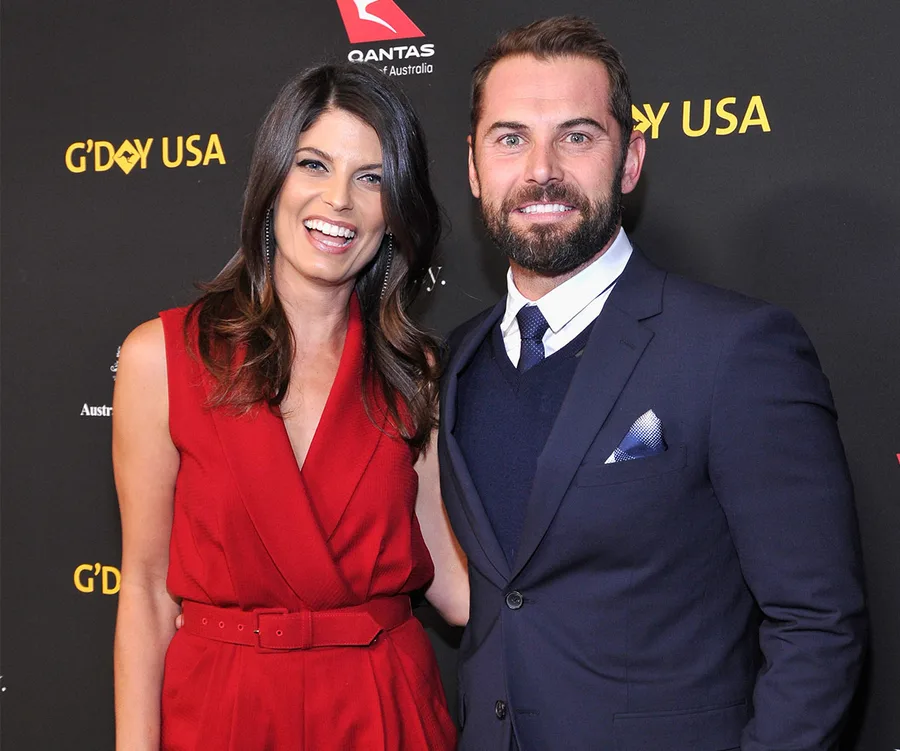 Couple in formal attire at a G'DAY USA event, smiling on the red carpet.