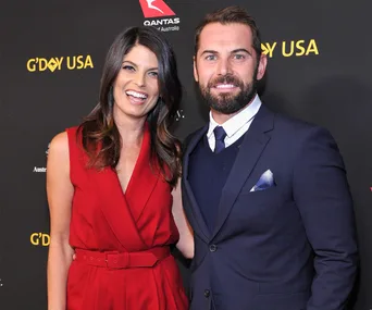 Couple in formal attire at a G'DAY USA event, smiling on the red carpet.