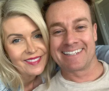A smiling couple taking a close-up selfie at home.