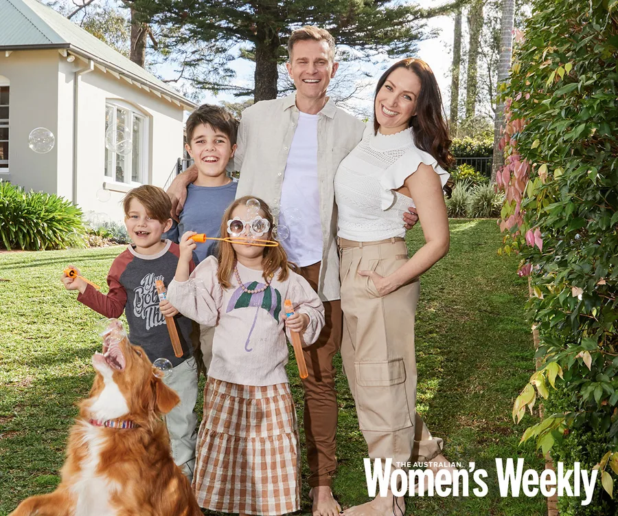 Family enjoying a sunny day in the yard with bubbles and a playful dog, featured in Women’s Weekly.