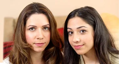 Two women sitting close together, looking at the camera with neutral expressions.