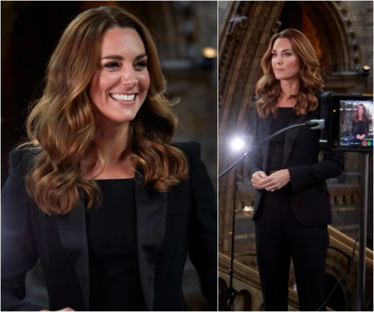 "Person in a black blazer smiling and speaking at an event, lighting equipment visible in the background."