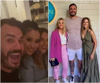 Group of friends smiling at dinner; three women and a man posing together outdoors, dressed casually chic.