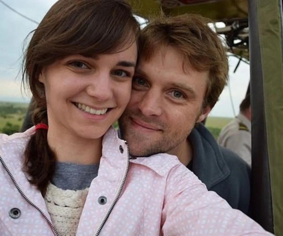 A smiling couple taking a selfie outdoors, with soft daylight illuminating their faces.