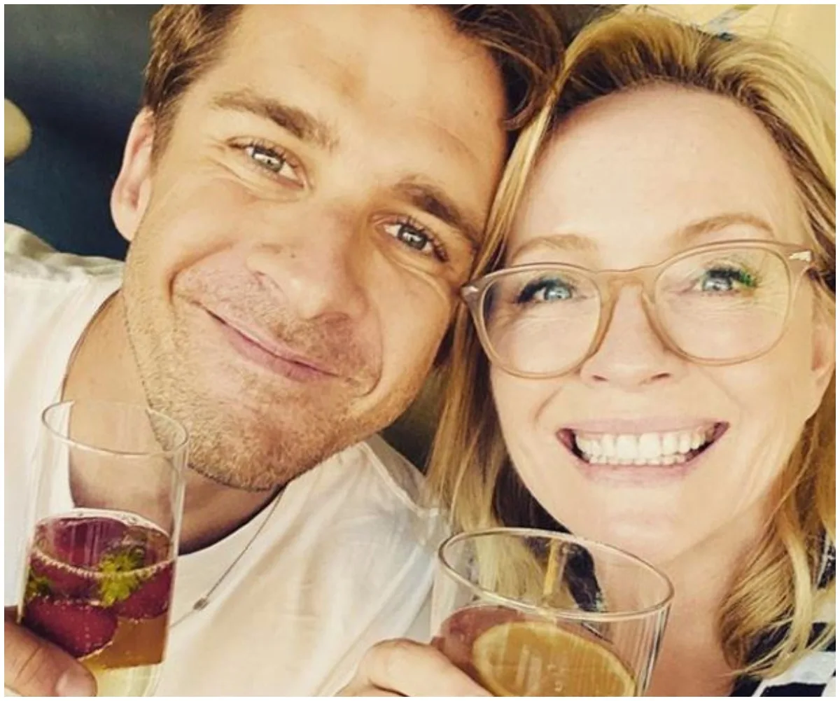 Two people smiling and holding drinks, close-up selfie.