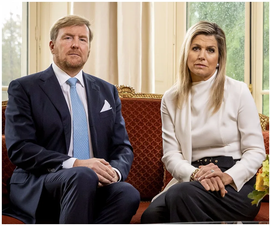 King Willem-Alexander and Queen Maxima seated together, delivering a formal address in elegant attire.