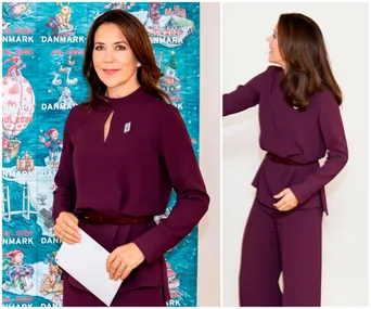 A woman in a purple outfit stands before a colorful backdrop and holds an envelope, her hair styled down.