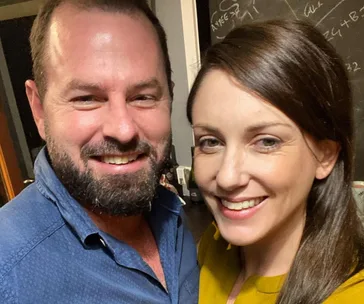 A smiling couple taking a selfie together indoors.