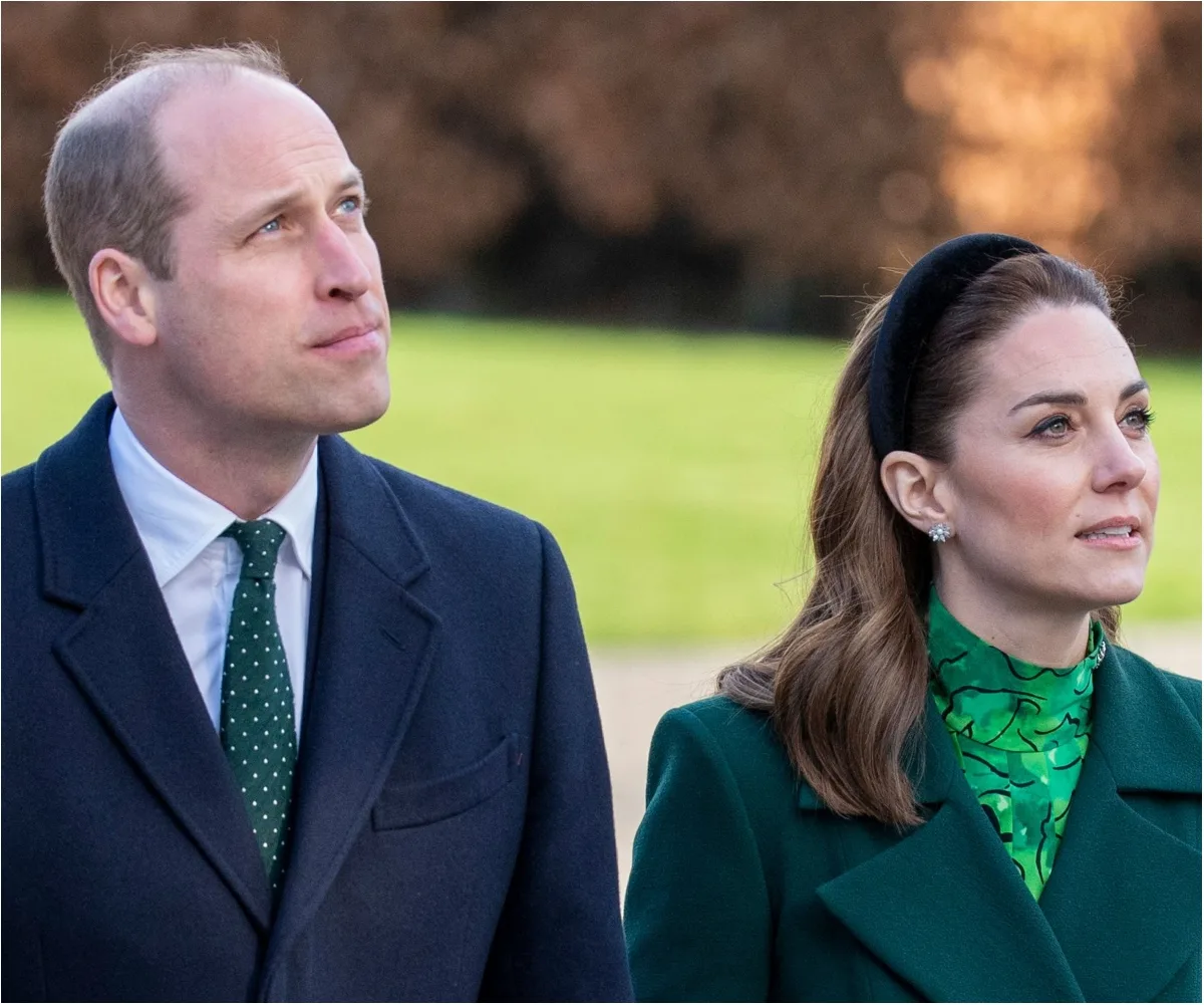 Two individuals, one in a dark coat and polka-dot tie, the other in a green outfit, looking upwards outside.