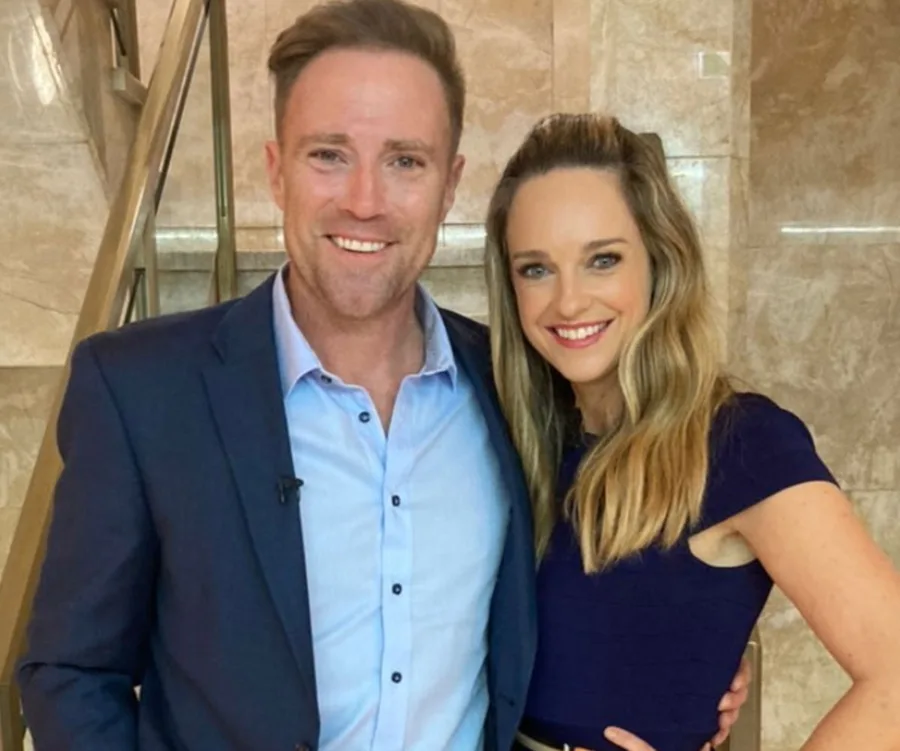 Man in blue suit and woman in dark dress smiling and posing together indoors.