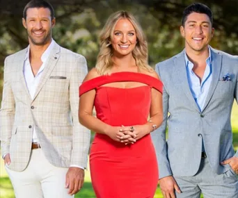 A woman in a red dress stands between two men in suits, outdoors.