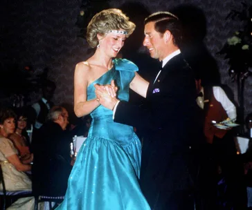 A couple dances gracefully at an elegant event, both smiling and dressed in formal attire.