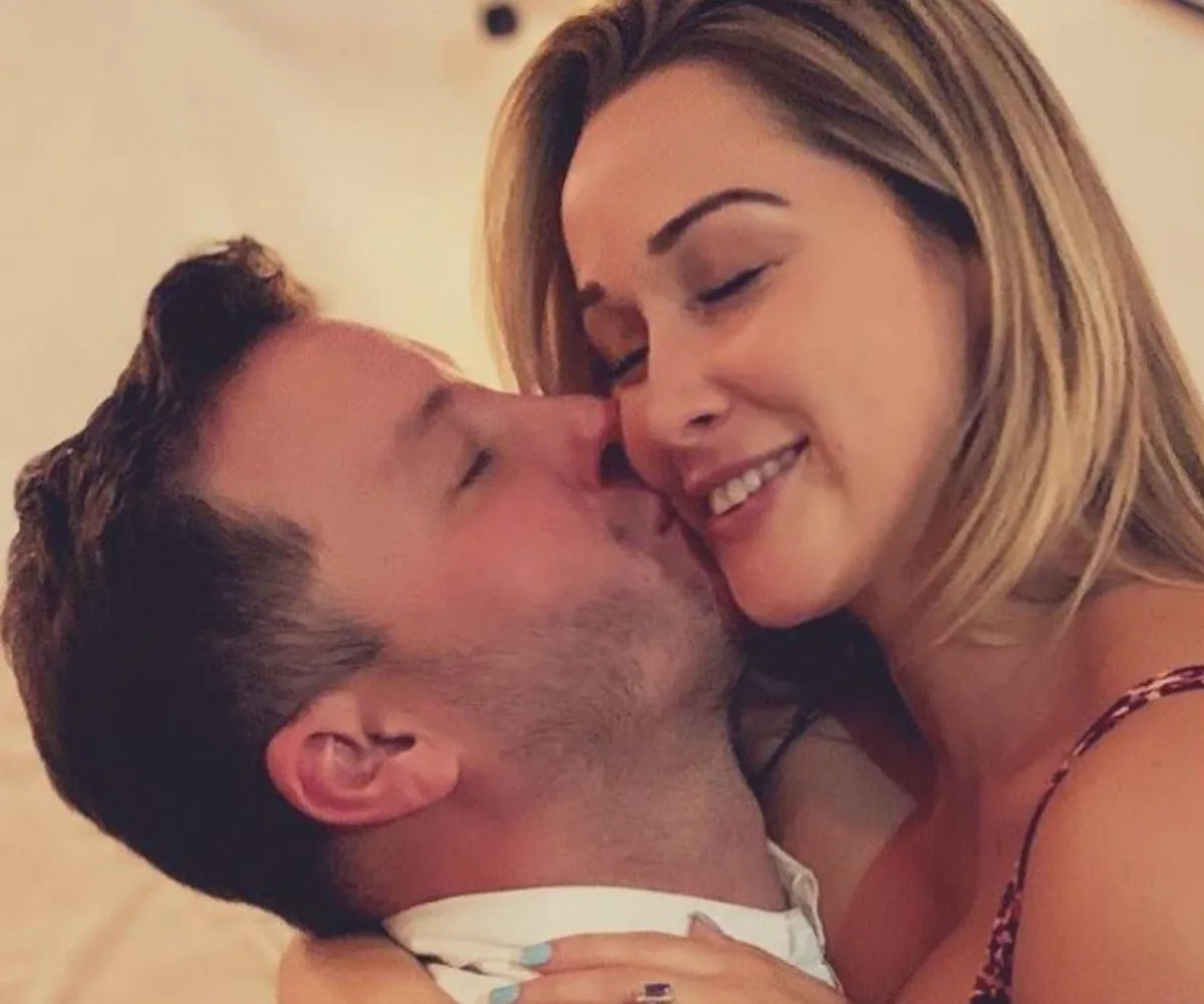 Couple embracing and smiling, man kissing woman's cheek warmly.