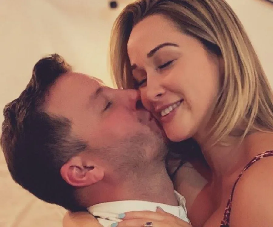 Couple embracing and smiling, man kissing woman's cheek warmly.
