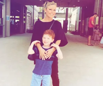 Mother and son smiling outside a school building.