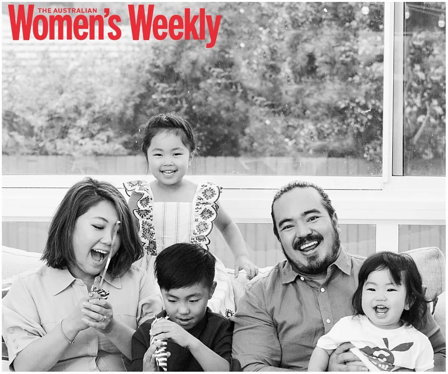 A family with two adults and three children smiling and playing together, featured in Australian Women’s Weekly magazine.