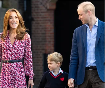 A woman in a floral dress, a man in a blue blazer, and a young boy smiling and walking together outdoors.