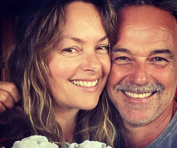 A smiling couple close up, both appear happy and relaxed, embracing each other warmly.