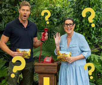 Two people in the jungle with question marks, holding a red phone and "I'm a Celebrity" clue cards.