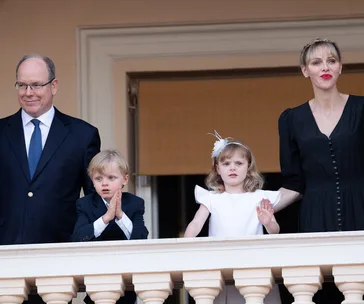 Family on a balcony: two adults with two children, the boy in a suit, the girl in a dress with a headpiece.