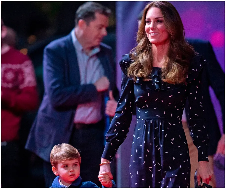Woman in a navy Alessandra Rich dress holding a child's hand at an event, with blurred people in the background.