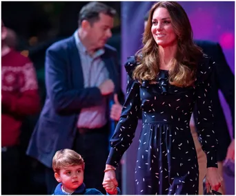 Woman in a navy Alessandra Rich dress holding a child's hand at an event, with blurred people in the background.
