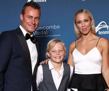 "A smiling family at an awards event, dressed in formal attire against a blue backdrop."