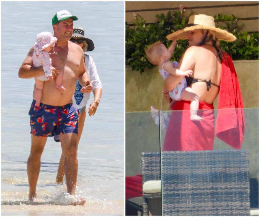 Man holding baby in ocean; woman with baby by poolside wearing sunhat, wrapped in a red towel.