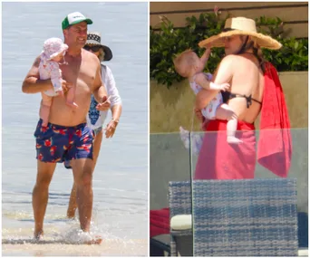 Man holding baby in ocean; woman with baby by poolside wearing sunhat, wrapped in a red towel.