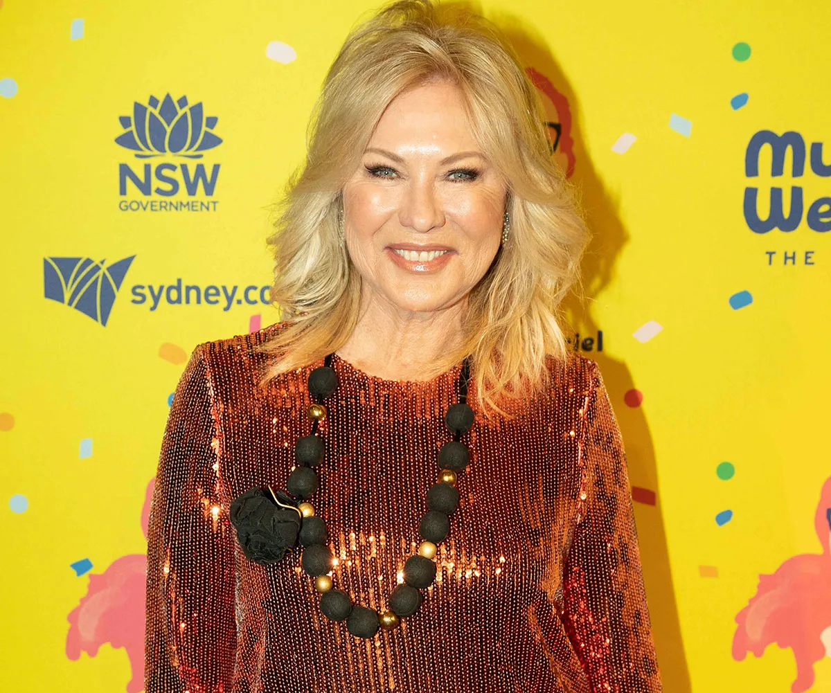 Person in a sequined outfit smiles in front of a colorful yellow backdrop with logos.