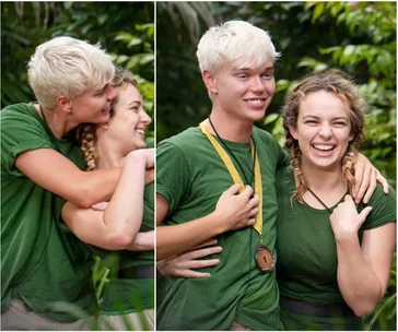 Two people in green shirts smiling and hugging in a lush outdoor setting; one wears a medal.