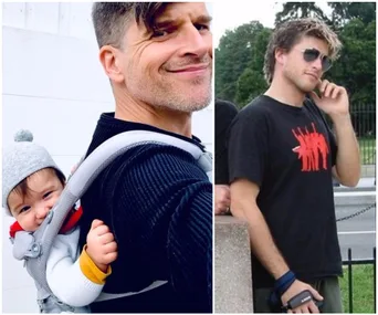 Father with baby in carrier smiling; beside, young man with sunglasses in a black t-shirt standing outdoors.