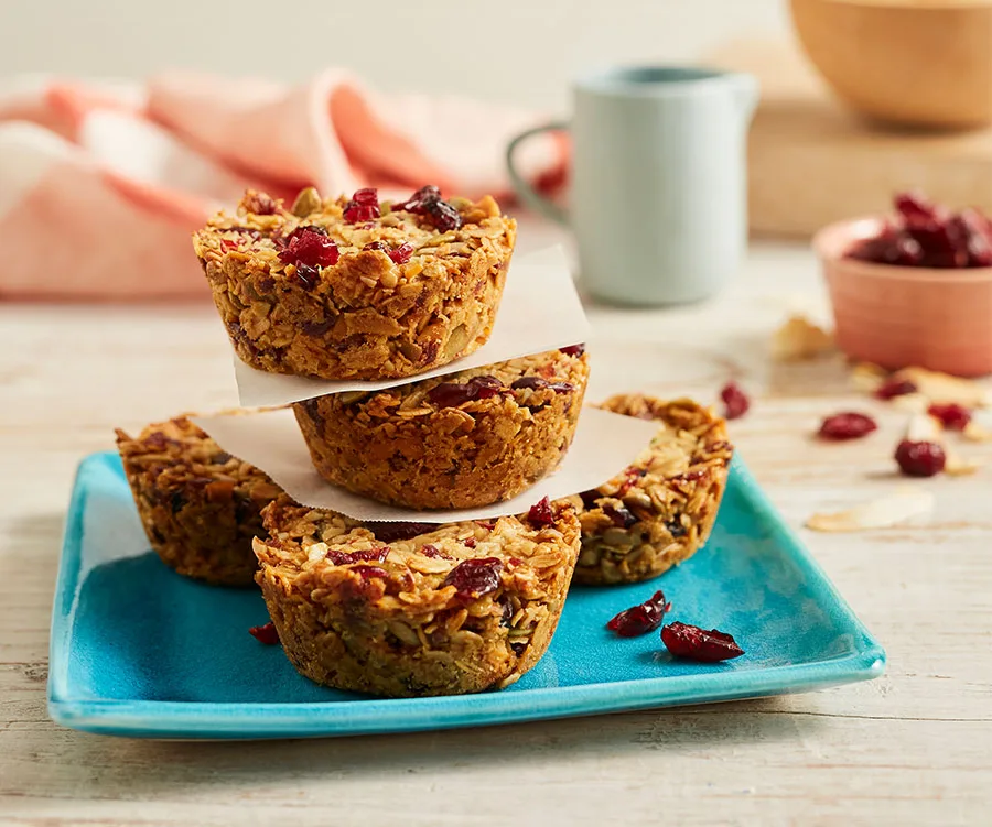 Stacked muesli cups with oats and cranberries on a blue plate, garnished with dried cranberries in a casual setting.