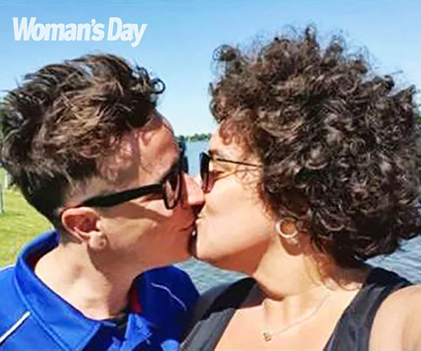 Two people kissing outdoors on a sunny day, with "Woman's Day" logo in the corner.