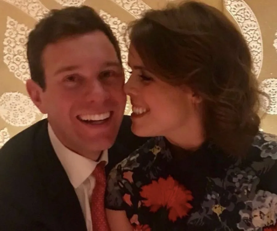 Couple smiling, embracing affectionately against a patterned background.