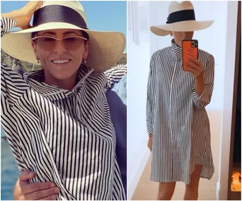 A person in a striped shirt dress and wide-brimmed hat, smiling outdoors and taking a mirror selfie indoors.