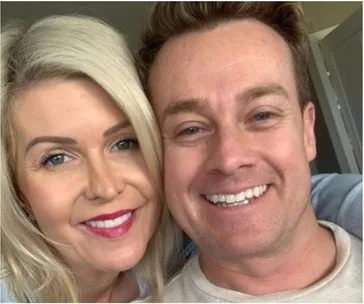 A couple smiling closely together for a selfie, both with light hair.