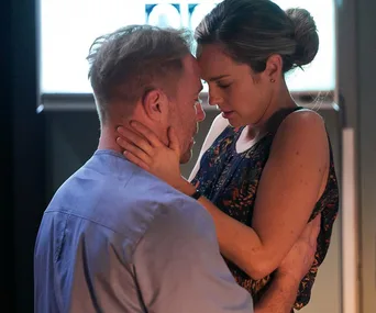 A man and woman in an intimate embrace, highlighting a tender moment indoors.