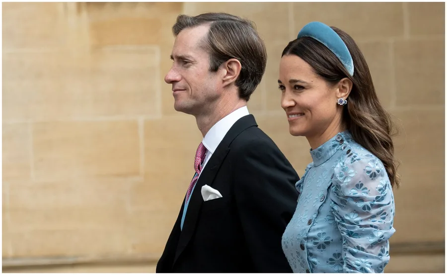 Couple walking side by side, dressed formally; woman in blue dress and headband, man in suit with pink tie.