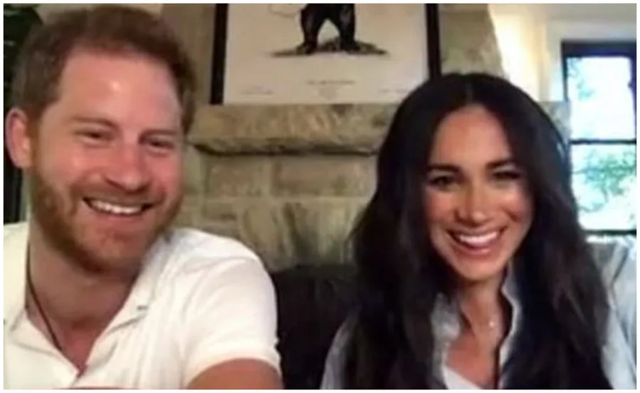 A smiling couple doing a video call from a cozy room with a stone fireplace and artwork in the background.
