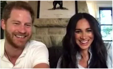 A smiling couple doing a video call from a cozy room with a stone fireplace and artwork in the background.