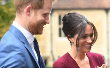 A smiling couple stands outdoors, both appearing happy and engaged in conversation.