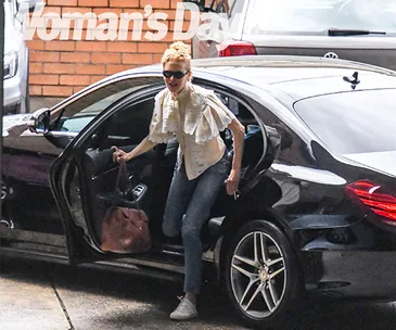 Nicole Kidman exits a black car, wearing sunglasses, jeans, and a white blouse, holding a handbag, with "Woman's Day" logo.