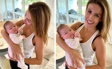 Woman in white tank top holding a smiling baby indoors, both appear happy and relaxed.