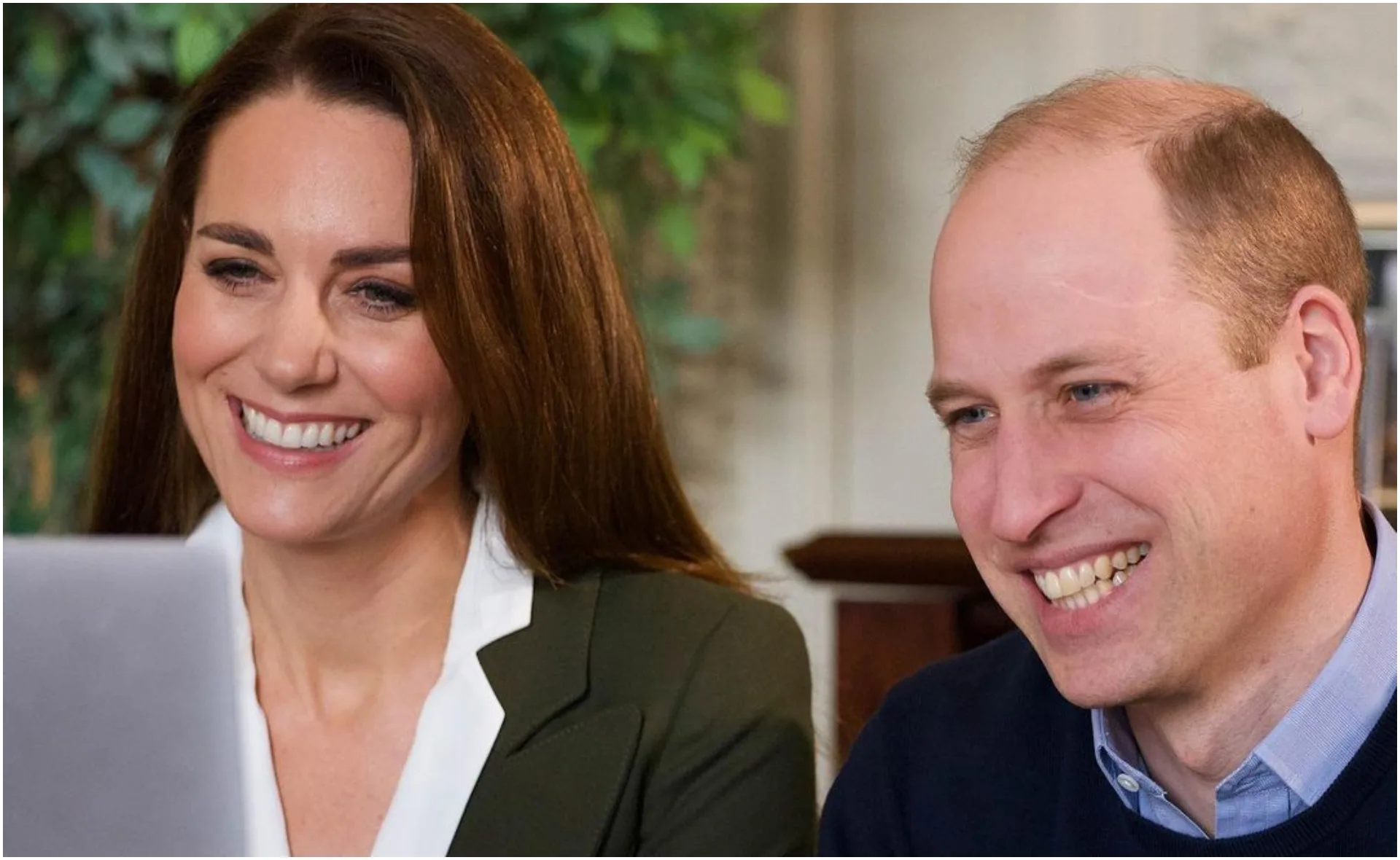 Two people smiling while looking at a computer screen together.