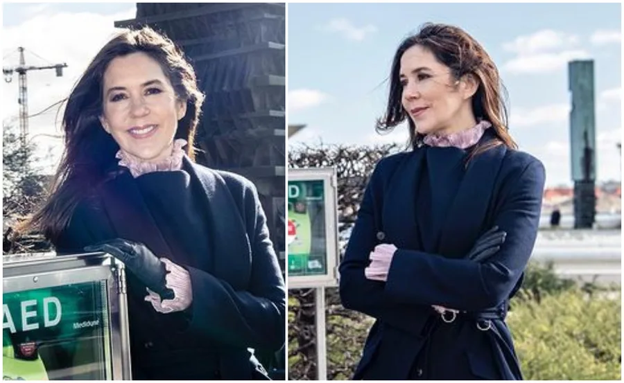 A woman in a dark coat stands beside an automated external defibrillator (AED) outdoors.