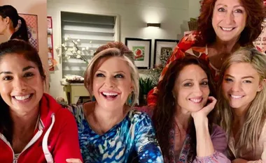 Women from "Home and Away" smiling together indoors, celebrating International Women's Day.